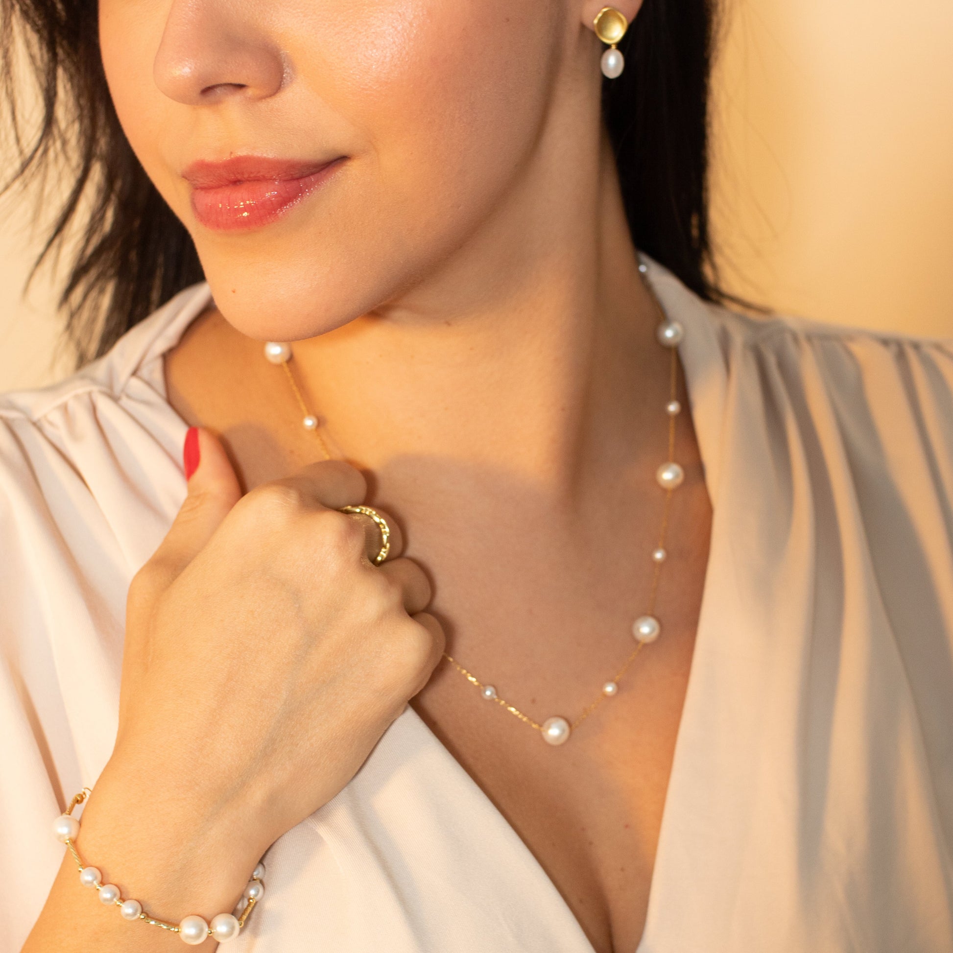 Woman wearing a pearl necklace and bracelet with a blurred background