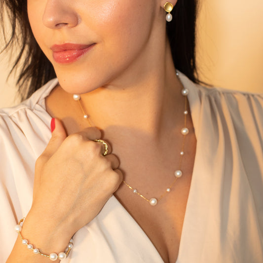 Woman wearing a pearl necklace and bracelet with a blurred background